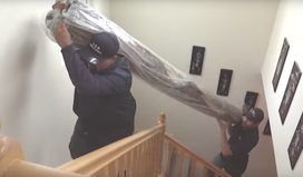 movers carrying large rug upstairs
